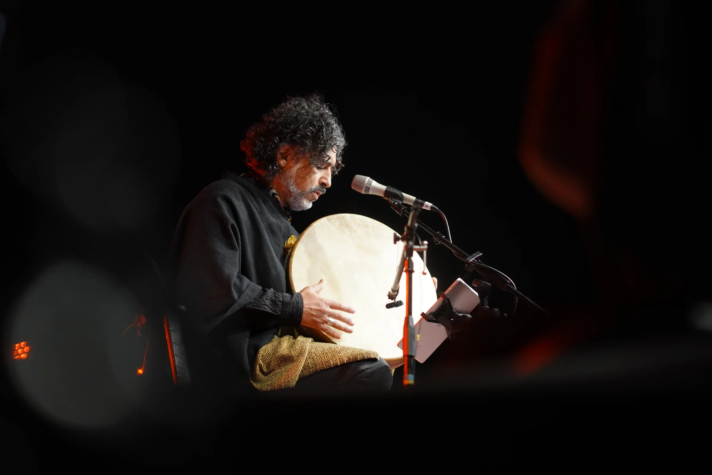 Percusionista tocando tambor de marco en escenario durante concierto