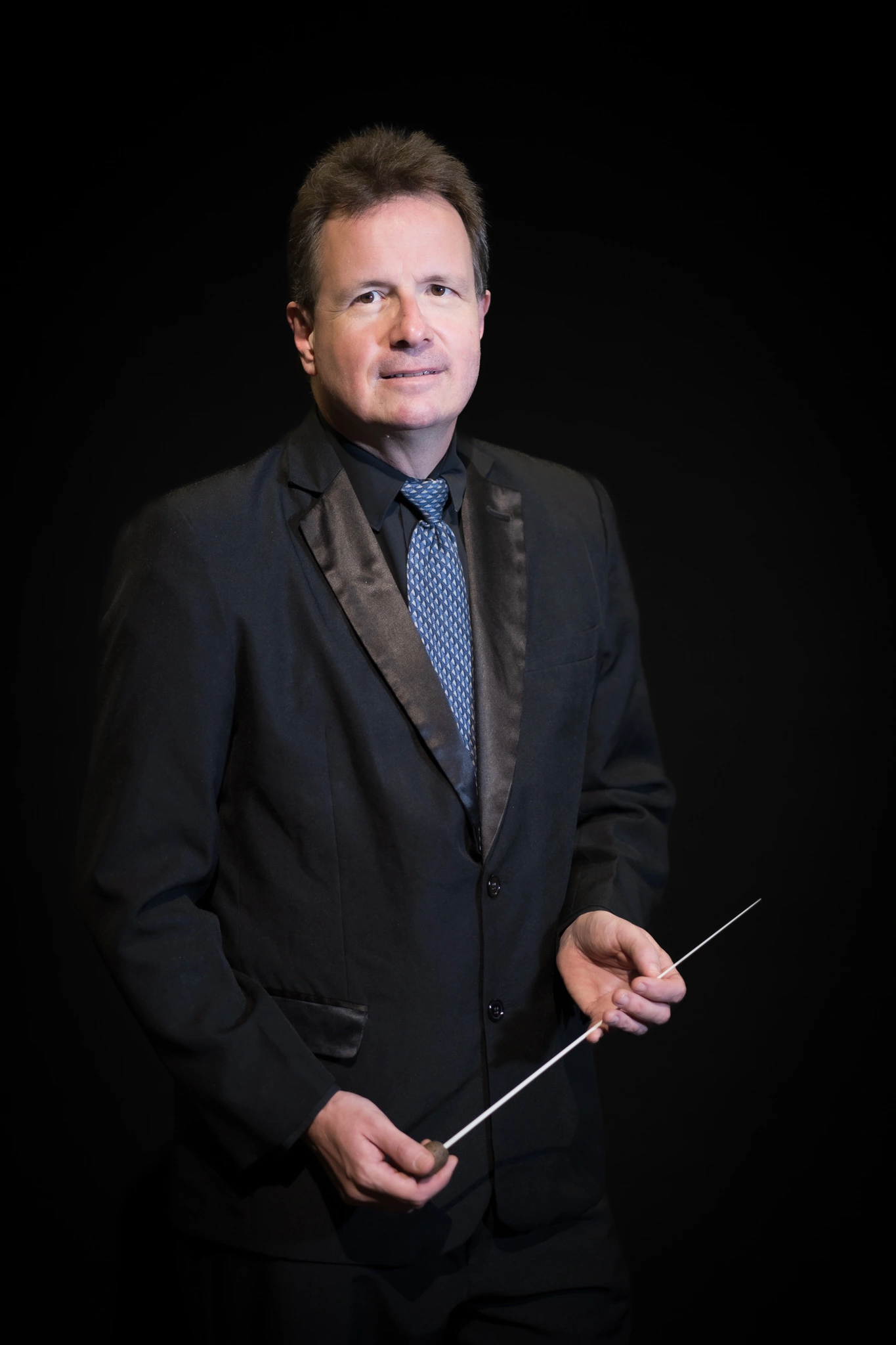 Retrato de director de orquesta en traje formal con batuta