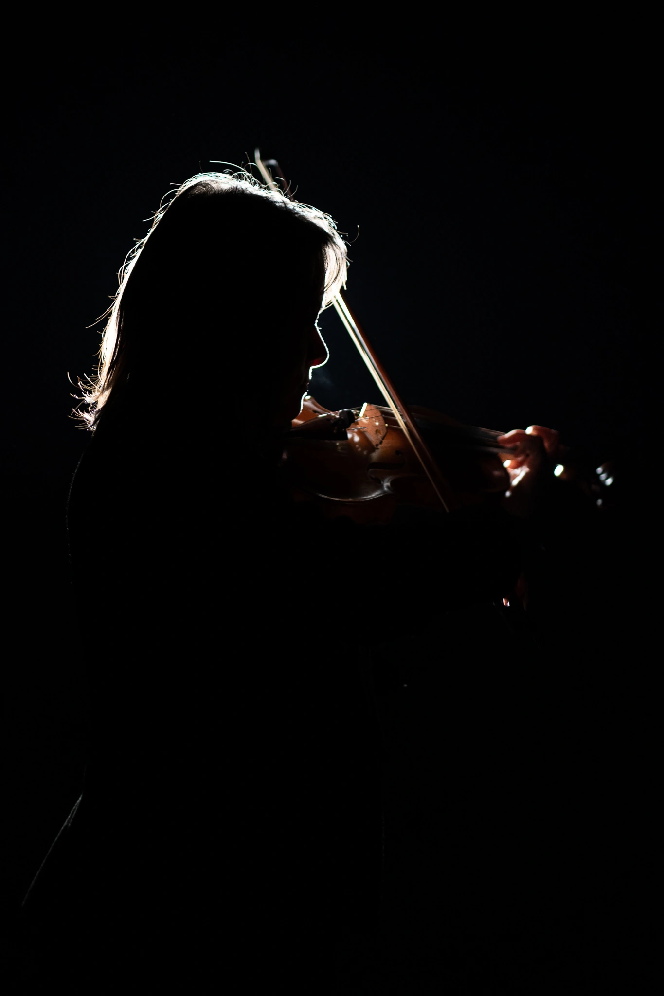Silueta en contraluz de violinista tocando su instrumento