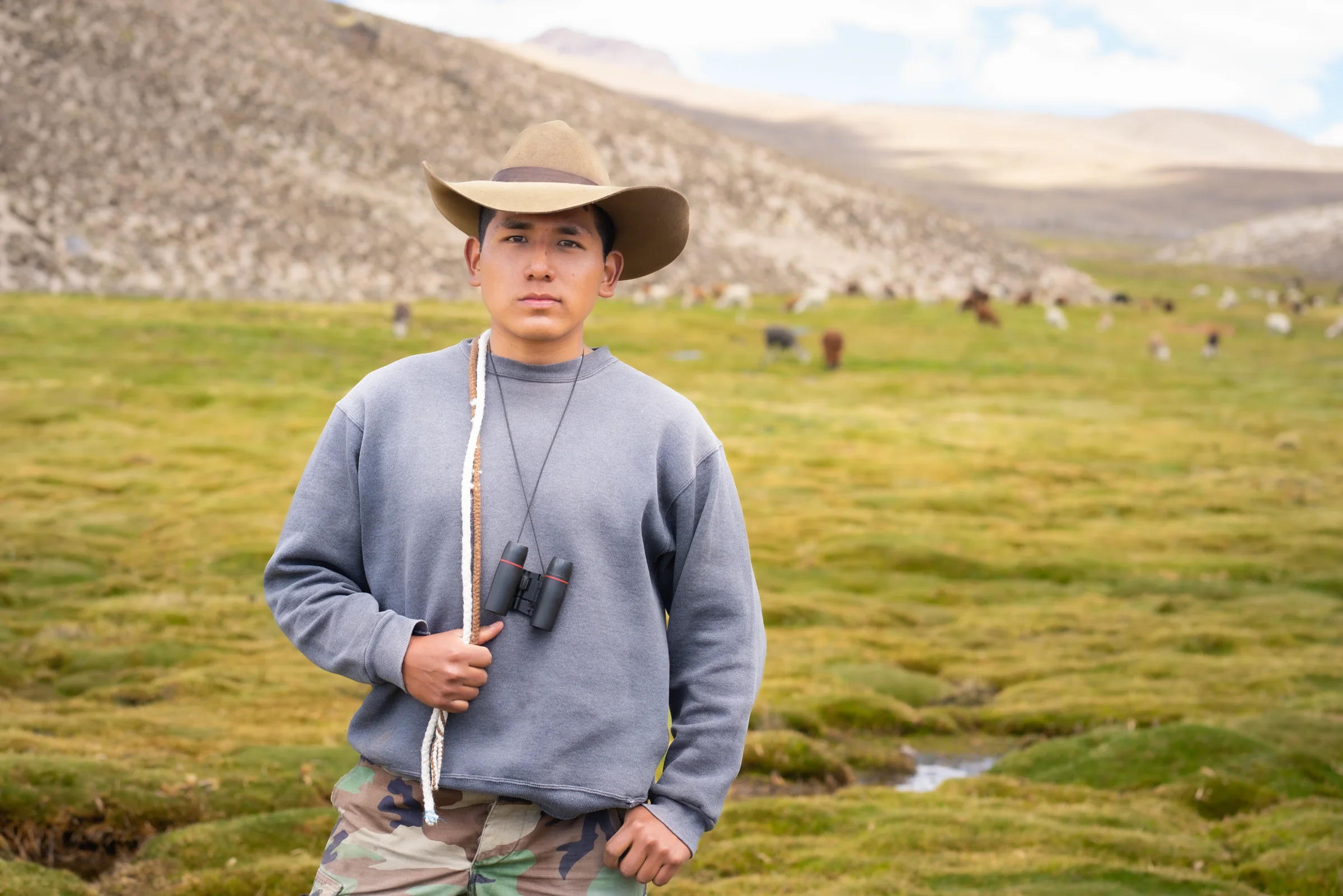 Joven con sombrero y binoculares en bofedal del altiplano