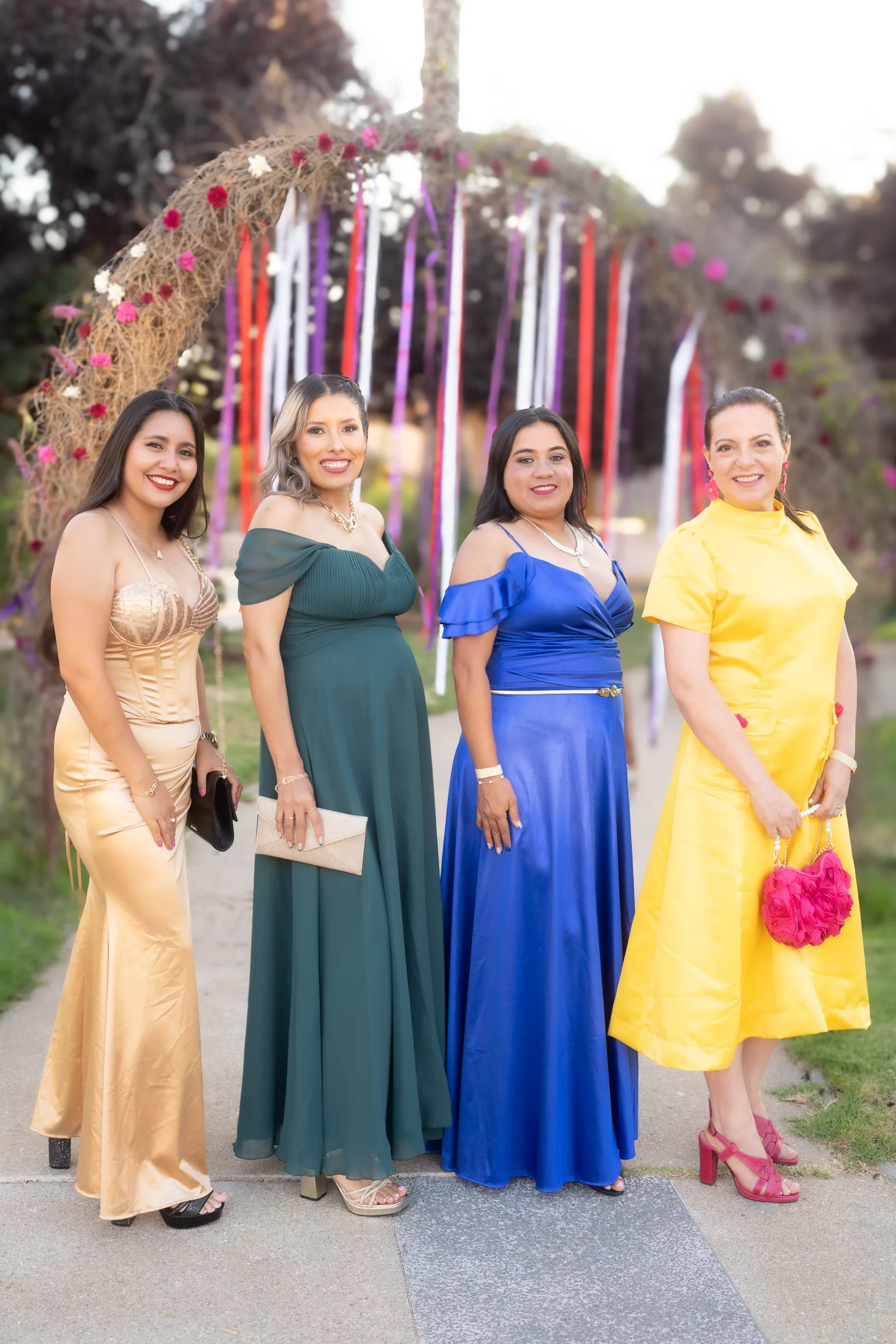 Invitadas a evento social posando junto a arco floral decorativo