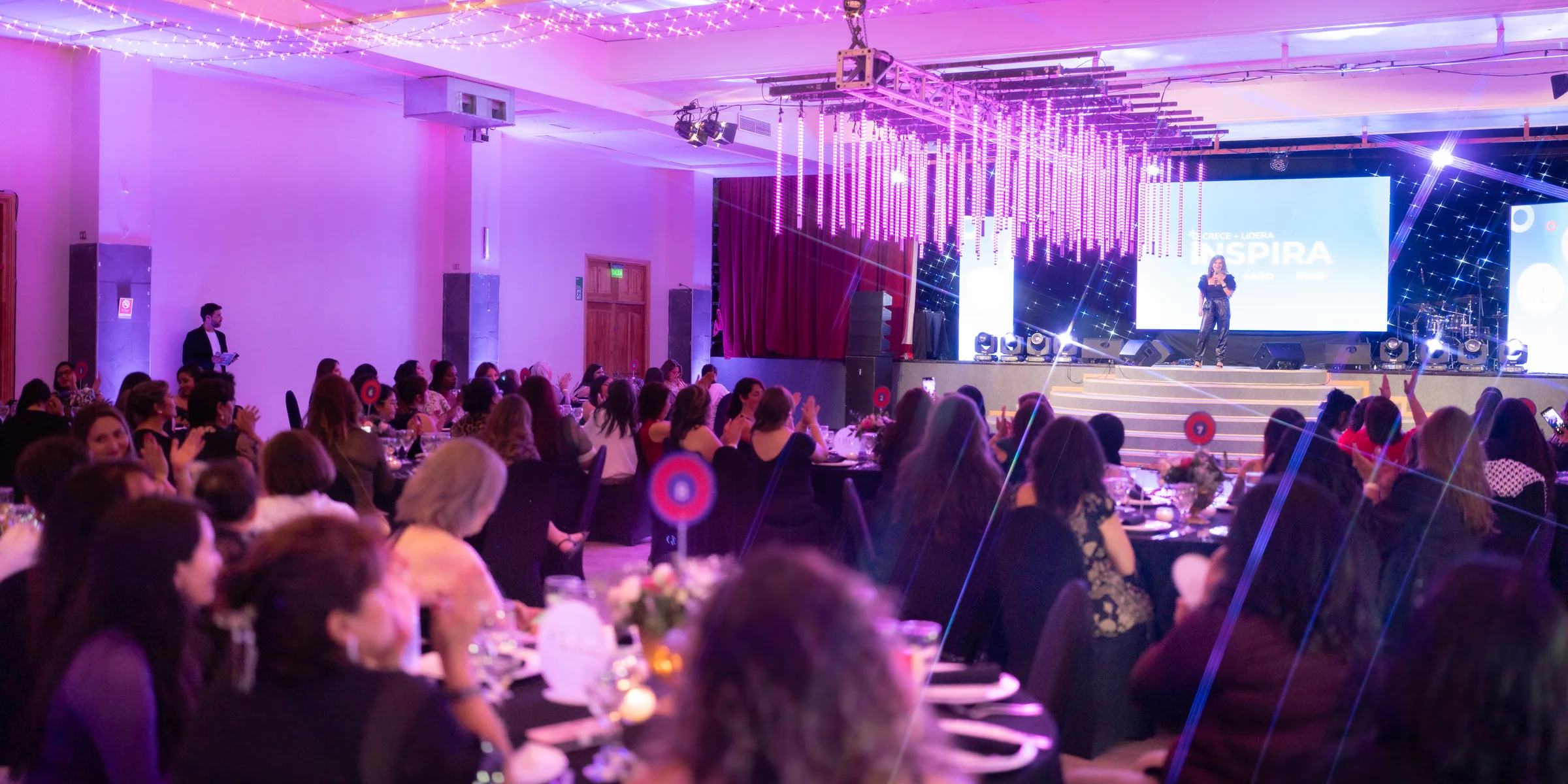 Salón de gala con mesas de banquete e iluminación escénica en evento corporativo