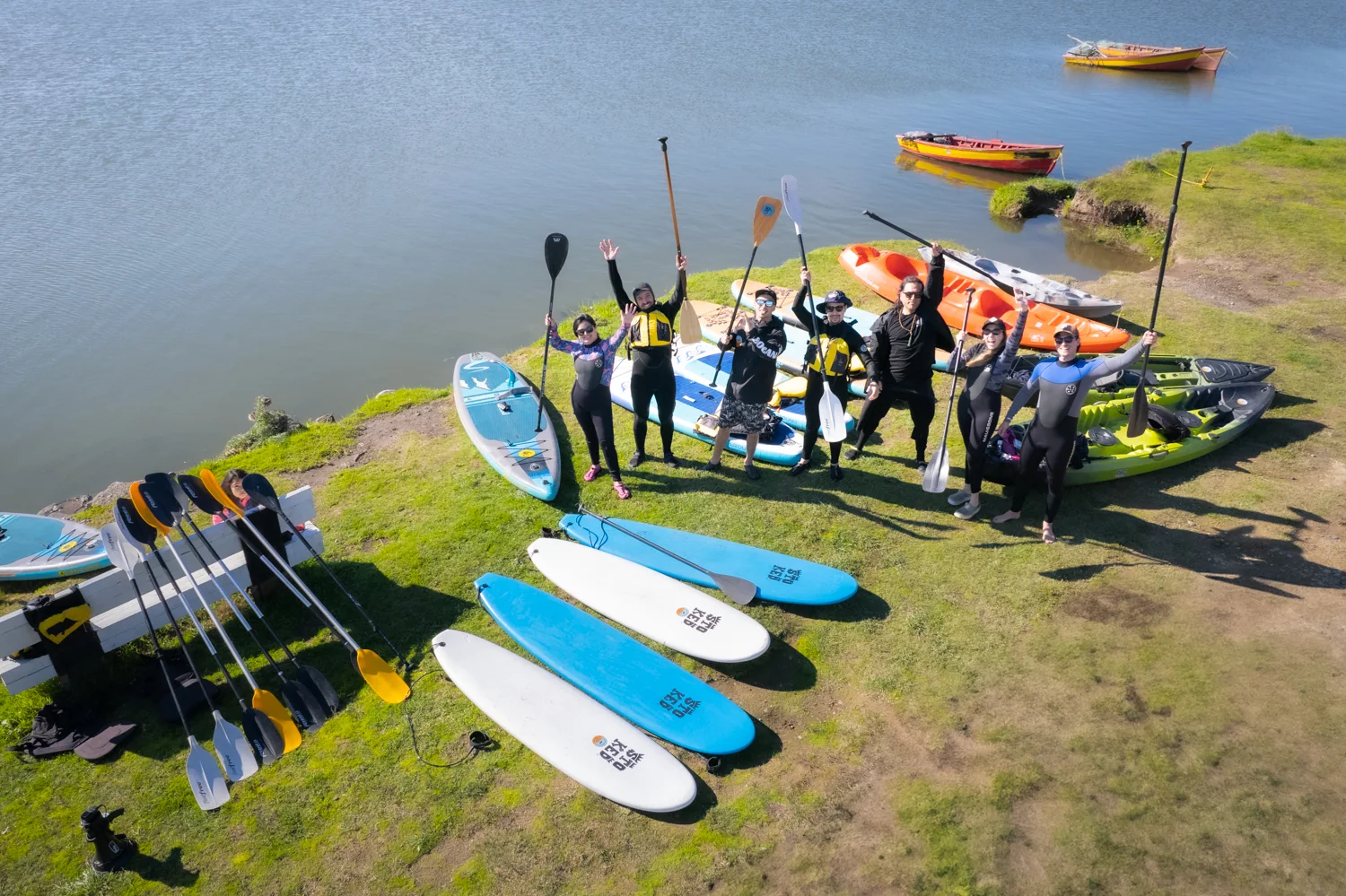 Grupo de deportistas con tablas de stand up paddle en la orilla de un lago