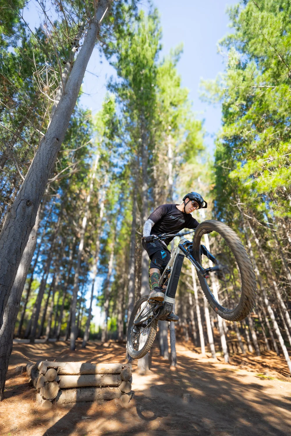 Ciclista de montaña saltando en rampa entre árboles de un bosque