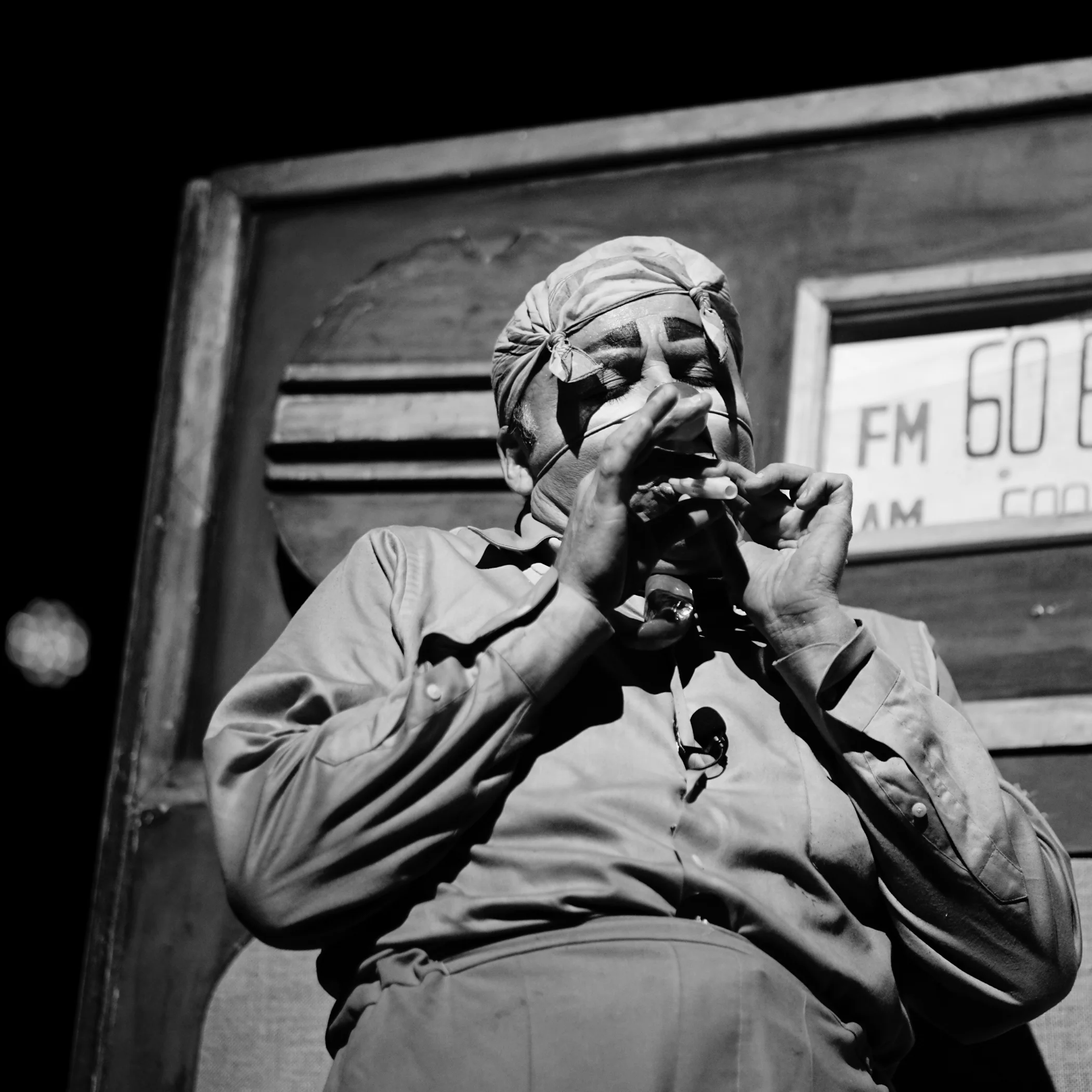 Actor caracterizado tocando la armónica en escena teatral en blanco y negro