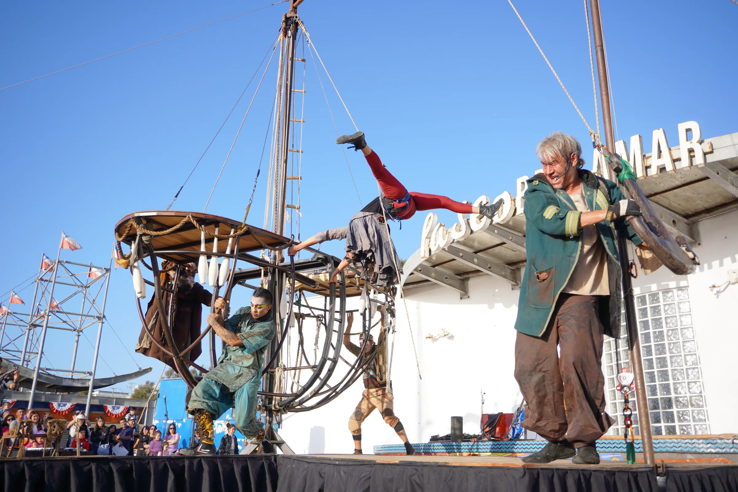 Compañía de teatro callejero con escenografía de barco y acróbatas